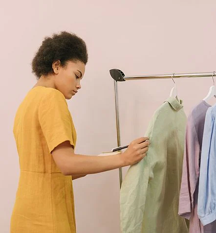 Lojista organizando as roupas da arara na loja